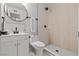 Well-lit bathroom with a modern vanity, a round mirror, and walk in shower with neutral colored tile at 6229 Cromwell Ave, Las Vegas, NV 89107