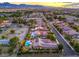 Aerial view capturing a neighborhood home with a swimming pool, solar panels, and lush greenery amidst a suburban landscape at 7111 Bath Dr, Las Vegas, NV 89131