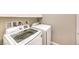 Modern laundry area with white washer and dryer units, and practical overhead storage at 7111 Bath Dr, Las Vegas, NV 89131