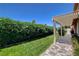 Backyard featuring lush green grass, patio cover with tile walkway and manicured hedge at 7761 Cowboy Trl, Las Vegas, NV 89131