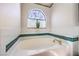Bathroom with a bathtub featuring a tile surround and a stained glass window at 8428 Apple Hill Ct, Las Vegas, NV 89128