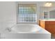 Elegant bathtub with tiled surround and textured glass window offers a serene, spa-like bathing experience at 8632 Skyward Ct, Las Vegas, NV 89145