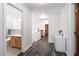 Bright hallway with wood-look floors leads to updated bathroom with natural wood vanity and white cabinetry at 9029 Tumblewood Ave, Las Vegas, NV 89143