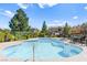 Community pool with lounge chairs and tables surrounded by mature trees and greenery at 9613 Eland Ct, Las Vegas, NV 89149