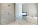 Modern glass enclosed shower with gray tiled walls next to soaking tub and double sided fireplace at 104 Tre Pietre St, Henderson, NV 89011