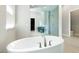 Bathroom with an oval soaking tub and large glass enclosed shower with gray tile walls at 104 Tre Pietre St, Henderson, NV 89011