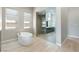 Bright bathroom with stand alone soaking tub, large glass enclosed shower, and wood look flooring at 104 Tre Pietre St, Henderson, NV 89011