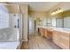 Bathroom with double vanity, shower, and bath, complete with well-lit mirrors at 11478 Bargetto Ct, Las Vegas, NV 89141