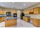 Spacious kitchen featuring light wood cabinets, granite countertops, an island and desk at 11478 Bargetto Ct, Las Vegas, NV 89141