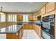 Bright kitchen featuring an island, wood cabinets, granite countertops, and modern appliances at 11478 Bargetto Ct, Las Vegas, NV 89141