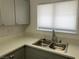 Close up of stainless steel sink, solid surface countertops and light gray cabinetry at 1501 Wintergreen Dr, Las Vegas, NV 89128