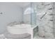 Bright bathroom featuring a soaking tub with steps and a glass-enclosed shower with marble-style tile surround at 1551 Echo Falls Ave, Las Vegas, NV 89183
