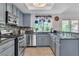 Bright kitchen features blue cabinets, granite countertops, stainless steel appliances, and a view from the large window at 1803 Candle Bright Dr, Henderson, NV 89074