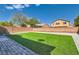 A backyard features green turf grass, a brick wall, and a stone border at 216 Sharp Edge Ave, North Las Vegas, NV 89031