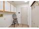 Utility room featuring white cabinets with wood trim, a utility sink, and a door with coat hooks at 2420 Desert Butte Dr, Las Vegas, NV 89134