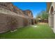Lush backyard with artificial turf, rock wall, and desert landscaping at 26 Costa Tropical Dr, Henderson, NV 89011
