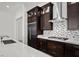 A modern kitchen boasts dark cabinets, stainless steel appliances, mosaic backsplash, and quartz countertops at 26 Costa Tropical Dr, Henderson, NV 89011
