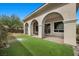 Charming covered patio with arched columns, manicured lawn, and mature trees at 26 Costa Tropical Dr, Henderson, NV 89011
