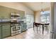 Modern kitchen featuring sage cabinetry, stainless steel appliances, and a sunlit breakfast nook at 2808 Cygnus St, Las Vegas, NV 89117