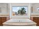 Bright bathroom features a large tub with a window overlooking a palm tree at 2846 Barrow Downs St, Las Vegas, NV 89135