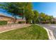 A community entrance with stone signage reading 'Wood Glen' amidst lush landscaping and a well-maintained lawn at 2846 Barrow Downs St, Las Vegas, NV 89135