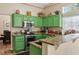 Bright kitchen features green cabinets, granite countertops, stainless steel appliances, and a breakfast bar at 2913 Laverton Dr, Las Vegas, NV 89134