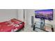 Bedroom featuring a bed with a red floral comforter, a small glass desk, and a wall-mounted television at 341 Waterwheel Falls Dr, Henderson, NV 89015