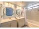 Bathroom features a double sink vanity, modern lighting, and tub with marble-look tile at 6961 Ray Charles Ln, Las Vegas, NV 89119