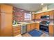 Well-equipped kitchen featuring wooden cabinets, stainless steel appliances, and brick accents at 6961 Ray Charles Ln, Las Vegas, NV 89119