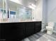 Bathroom with dual sinks, granite countertops, dark cabinets, and gray wood-look flooring at 8125 Rio De Janeiro Dr, Las Vegas, NV 89128