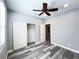 Bedroom with gray walls, ceiling fan, wood-look floors, closet, and hallway access at 8125 Rio De Janeiro Dr, Las Vegas, NV 89128