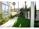 Well-maintained backyard featuring artificial turf, mature landscaping along a white wall, and a narrow walkway at 9440 Grenville Ave, Las Vegas, NV 89134