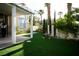 Spacious backyard featuring artificial grass, mature landscaping, a covered patio and a manicured lawn at 9440 Grenville Ave, Las Vegas, NV 89134