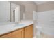 Bright bathroom featuring a single sink, wood cabinet, framed mirror, and shower-tub combo at 9975 Sand Key St, Las Vegas, NV 89178