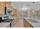Bright kitchen featuring wood flooring, stainless steel appliances, granite countertops, and wooden cabinets at 9975 Sand Key St, Las Vegas, NV 89178