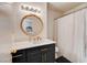 Updated bathroom featuring a black vanity, gold hardware, round mirror, and shower with a white curtain at 3322 Dragon Fly St, North Las Vegas, NV 89032