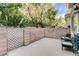 Private outdoor patio area with concrete flooring, brick walls, mature trees and black patio chairs at 3322 Dragon Fly St, North Las Vegas, NV 89032