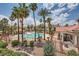 Community pool with a tile roofed building, lush landscaping, and shade structures at 605 Devonhall St # 201, Las Vegas, NV 89145