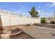 A backyard with a tall wooden fence, a large tree, and a brick-edged concrete patio at 6325 Orions Tool St, North Las Vegas, NV 89031
