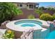 Relaxing in-ground hot tub with rock accents, surrounded by palm trees and lush greenery, offering a private retreat at 7538 Mustang St, Las Vegas, NV 89131