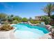 Sparkling pool with rock features surrounded by palm trees, lush plantings, and cozy outdoor seating areas at 7538 Mustang St, Las Vegas, NV 89131