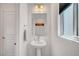 Stylish powder room featuring a pedestal sink, modern lighting, and a window providing natural light at 7756 Seville Estates Ct, Las Vegas, NV 89113