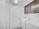 Bright laundry room with a white washer and dryer, gray cabinets and a clean, functional design at 7756 Seville Estates Ct, Las Vegas, NV 89113