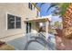 A covered patio with concrete slab surrounded by rocks, vegetation, and palm trees at 7973 Macklin St, Las Vegas, NV 89129