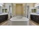 Modern bathroom featuring dual vanities, dark wood cabinets, a soaking tub, and private water closets at 7998 W Ford Ave, Las Vegas, NV 89113