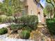 The side of this tan two story home features mature landscaping including small trees, rocks and green ground cover at 8550 Bright Bush St, Las Vegas, NV 89131