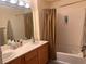 Bathroom featuring double sinks, wood cabinets, and a shower-tub combination with a curtain at 87 E Agate Ave # 202, Las Vegas, NV 89123