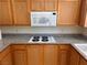 Kitchen cooktop featuring oak cabinets, granite counters, and updated appliances at 87 E Agate Ave # 202, Las Vegas, NV 89123