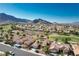 An aerial view showcases a community with red-tiled roofs, lush landscaping and mountain views at 10504 Button Willow Dr, Las Vegas, NV 89134