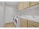 Well-lit laundry room featuring a washer, dryer, sink, and storage cabinets at 1305 Chaparral Summit Dr, Las Vegas, NV 89117
